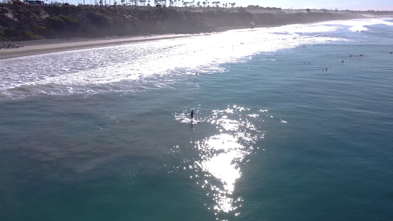 Una magnifica ripresa aerea con drone di un uomo che fa SUP nell'oceano vicino alla spiaggia, Carlsbad State Beach - California.