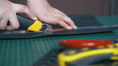 skilled designer cuts leather cloth with box cutter closeup