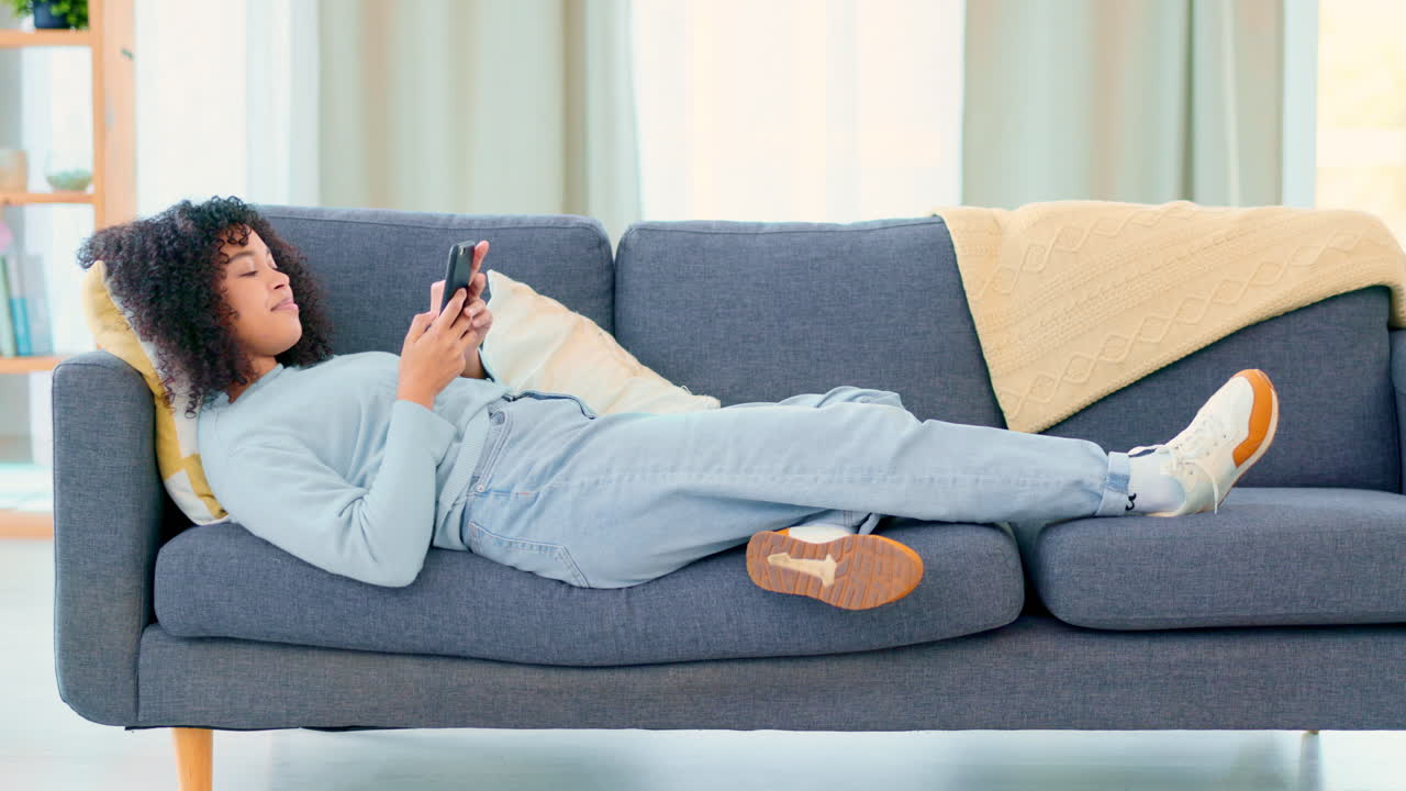 소파에서 휴식을 취하는 동안 트렌디한 여성 문자 메시지