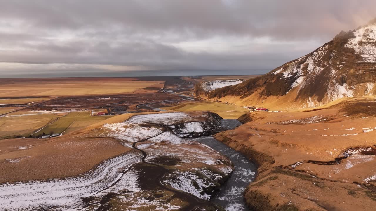 aerial - Skógá River meandering through snowy farmland, south Iceland