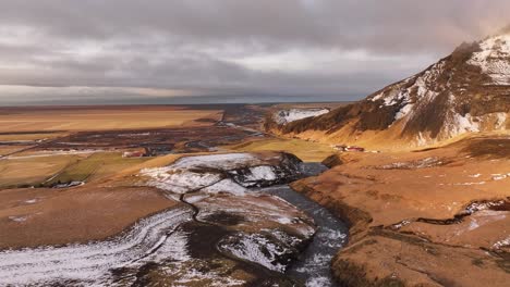 aerial - skógá river meandering through snowy farmland, south iceland