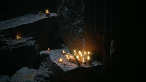 subtle glow of candles illuminating dark rock formations in cave setting