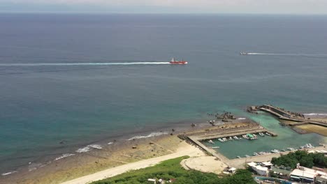 Spectacular-aerial-dolly-in-shot-from-Baishawei-harbor-overlooking-at-ferryboat-passing-by-a-fishing-boat-at-Xiaoliuqiu-Lambai-Island,-Pingtung,-Taiwan