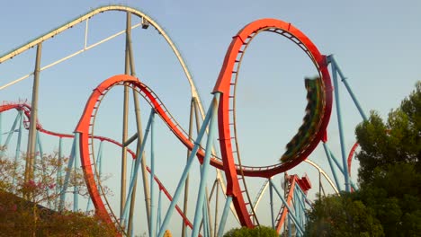 Low-angle-shot-of-cobra-roll-in-dragon-rollercoaster-inside-Port-Aventura-amusement-park-in-Salou,-Spain-during-evening-time