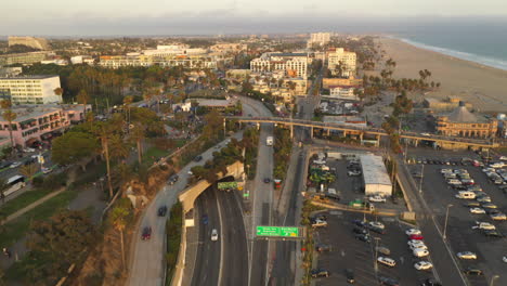 Parking-lot-at-the-Beach-of-Santa-Monica,-Los-Angeles-in-beautiful-Sunset-Golden-Hour-California-Vibe-with-birds-passing-by,-Aerial-Wide-tilt-up-shot,-Dolly-forward