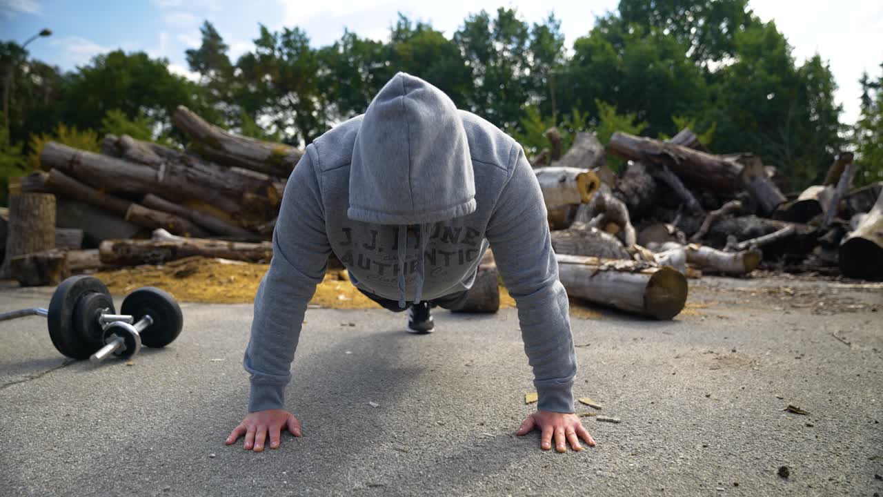 Motivated Man In Hoodie Jacket Doing Push Ups On The Ground Outdoor
