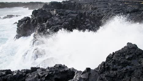 white foam wave splashing through black basalt rock shore, iceland, slow motion