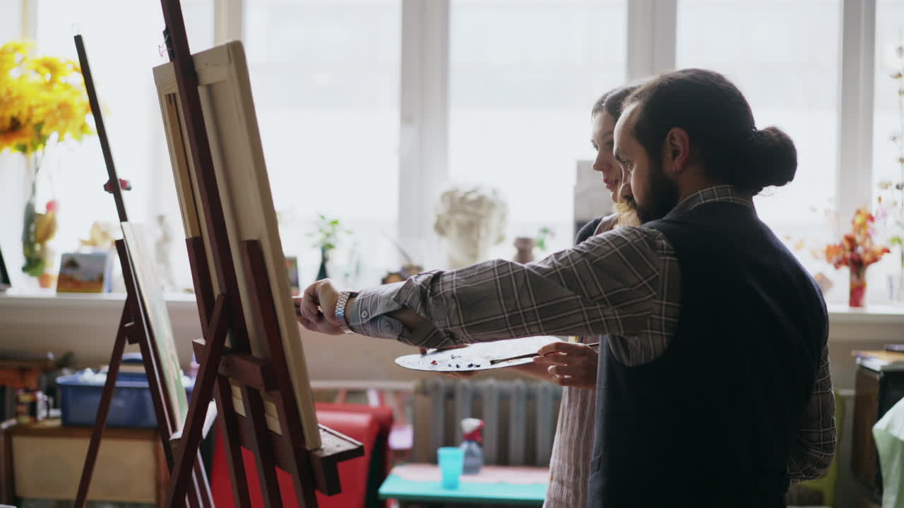 Art student learning painting from instructor in studio