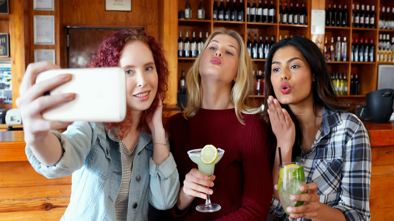 amigas tomando selfies con el teléfono móvil mientras toman bebidas 4k