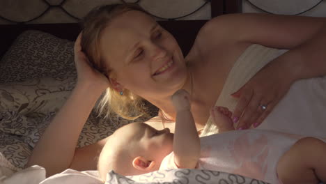 mum spending time with baby lying on bed together