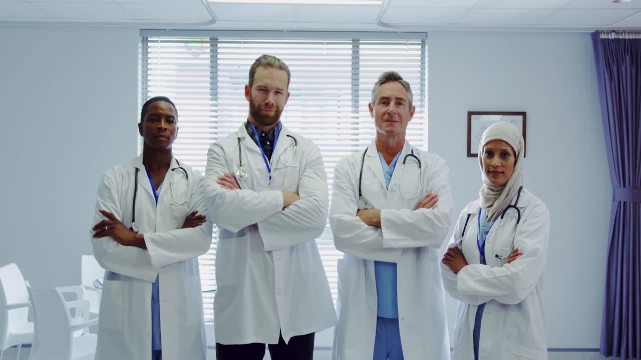 Front view of Multi-ethnic doctors standing together with arms crossed at hospital