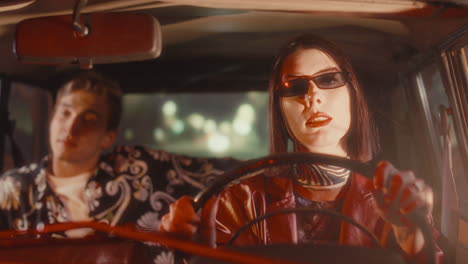 woman singing and driving vintage car at night with passenger in back seat