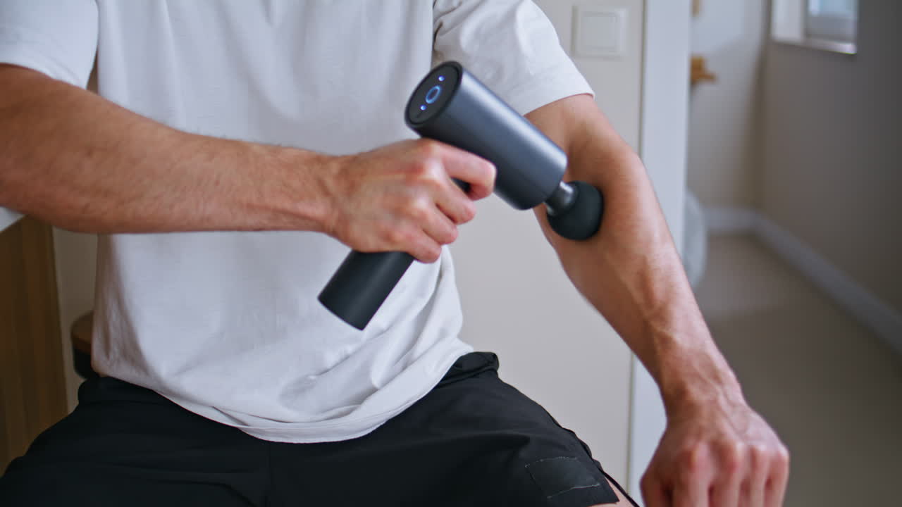 Athlete using electronic massager after active sport training at home closeup