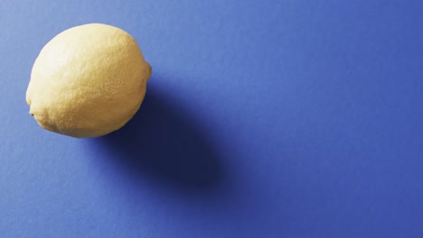 Video-of-close-up-of-lemon-with-copy-space-over-blue-background