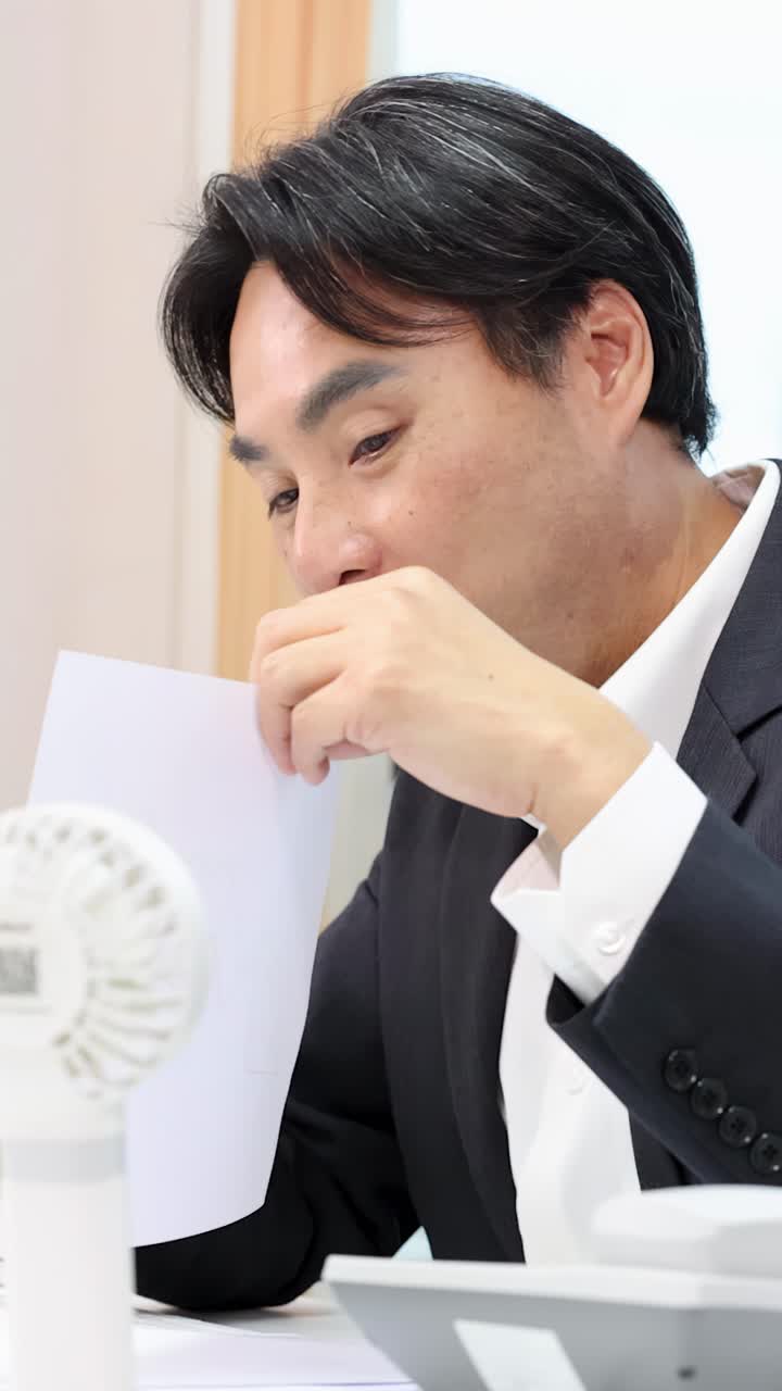 明るいオフィス会議中に、スーツを着たプロフェッショナルなアジア人ビジネスマンが書類について話し合う