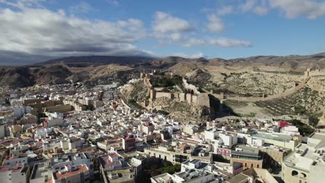 vista aérea sobre el paisaje urbano, hacia el castillo de la muralla de jairán en almería, españa - dando vueltas, disparo de drones