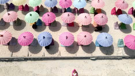 aerial top down view of young girl lying at beach during summertime in front of colorful umbrellas