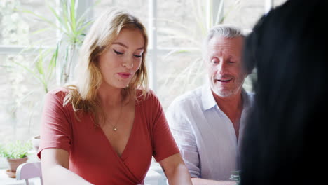 senior man sitting at table talking with friends during lunch at a restaurant, close up