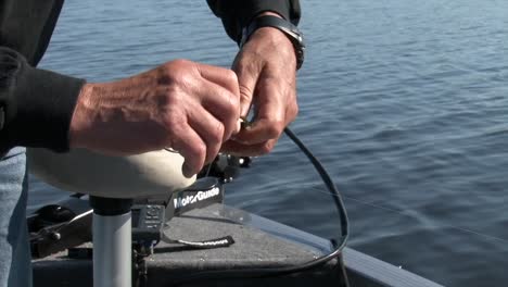 pescador en un barco poniendo sanguijuelas en el gancho de pesca