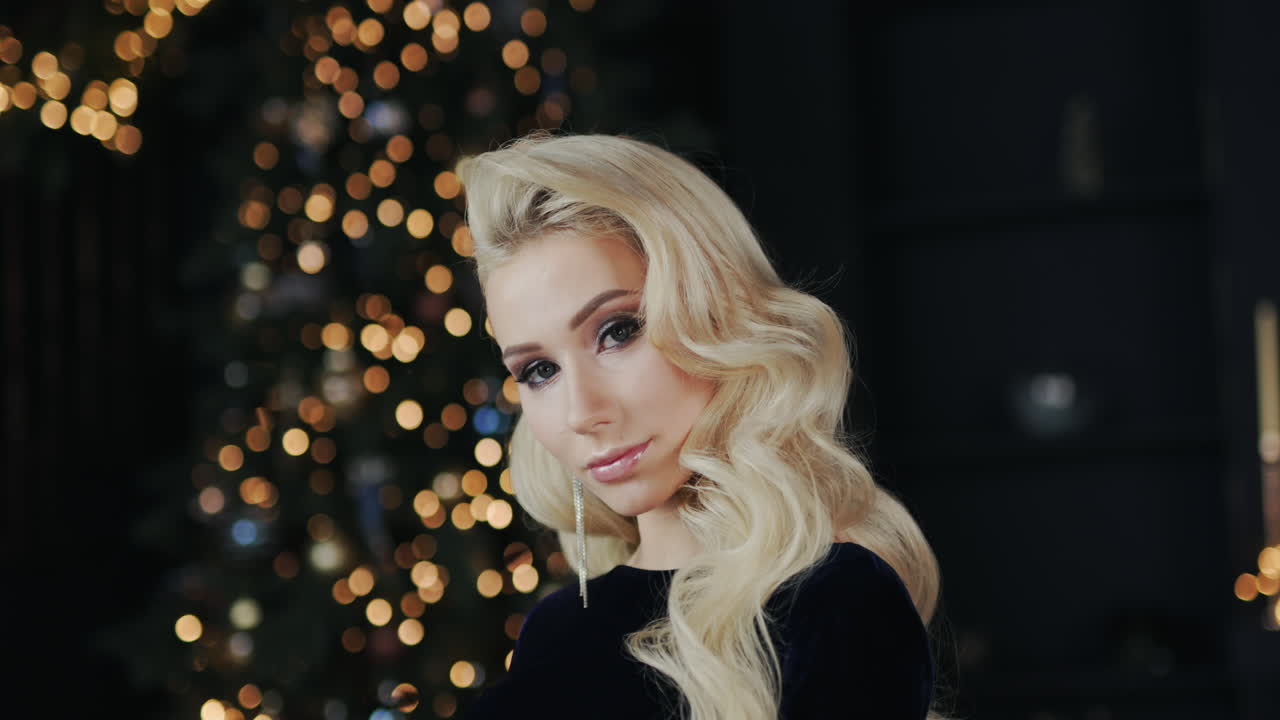 attraktiv ung kvinde på baggrund af uskarpe lys fra juletræet