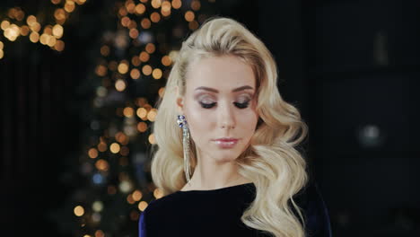 attractive young woman on background of blurry lights of christmas tree