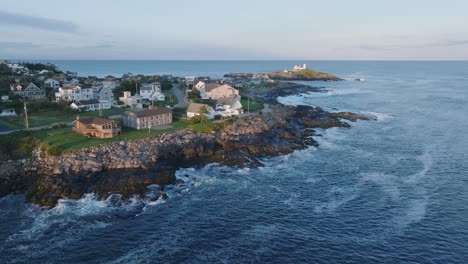 tomada aérea de un dron de york beach, maine, volando hacia el faro de cape neddick nubble al atardecer