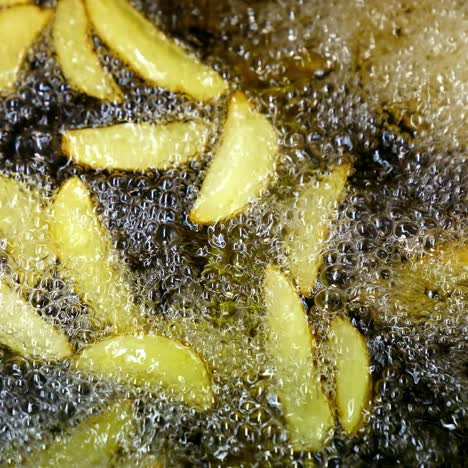 crispy potato in boiling oil. bubbles of hot oil during cooking french fries in deep fryer. process of cooking golden fried potatoes. macro shot