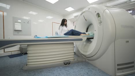 female patient is undergoing ct or mri scan under supervision of a radiologist in modern medical clinic. patient lying on a ct or mri scan bed, moving outside the machine.