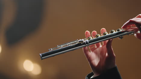 symphonic orchestra concert closeup of flute in hands of flutist old opera house or modern music hall