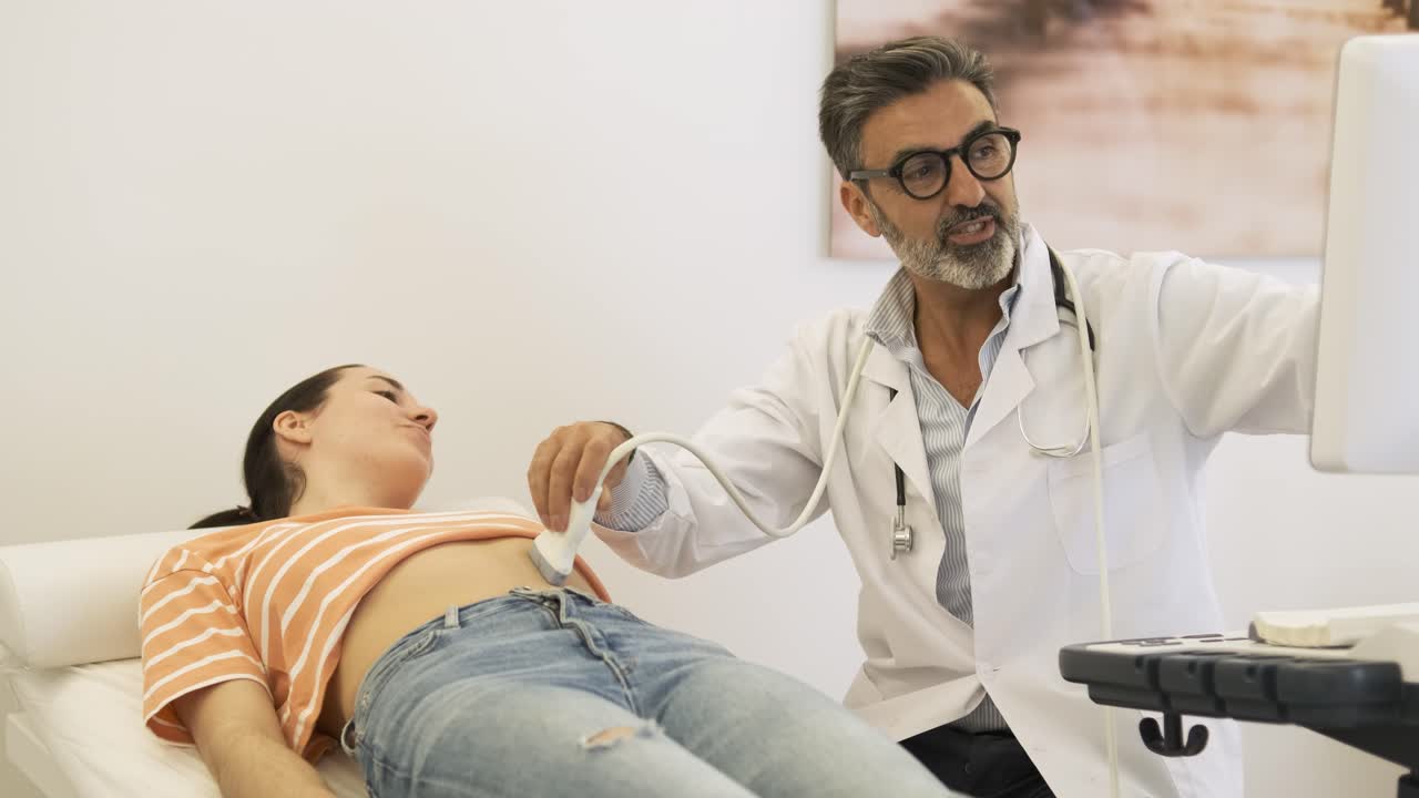 Smiling male doctor doing ultrasound of stomach