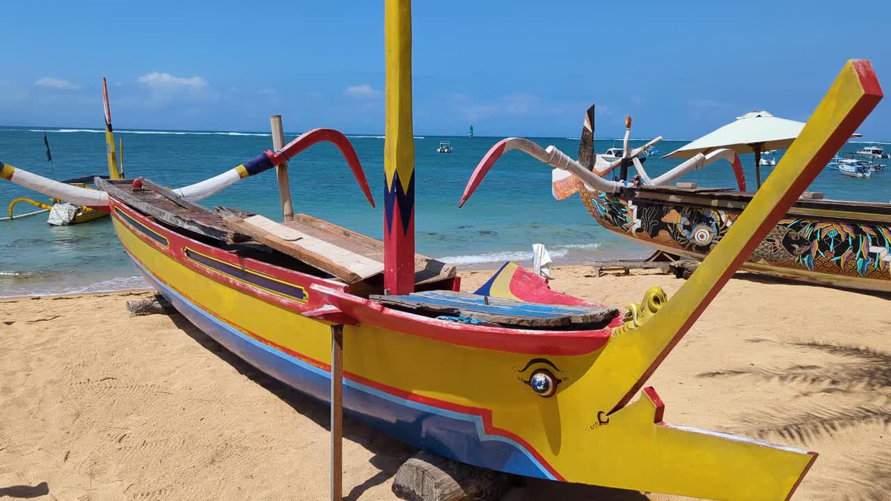 Colorate imbarcazioni tradizionali da pesca a bilanciere dipinte su una spiaggia a Sanur, Bali, Indonesia