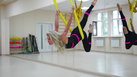 La-Chica-Practica-Aero-Yoga-En-Un-Estudio-Blanco-Volando-Sobre-El-Suelo-Sobre-Los-Lienzos-En-Cámara-Lenta.-Relajación-Y-Relajación-A-Través-Del-Estiramiento