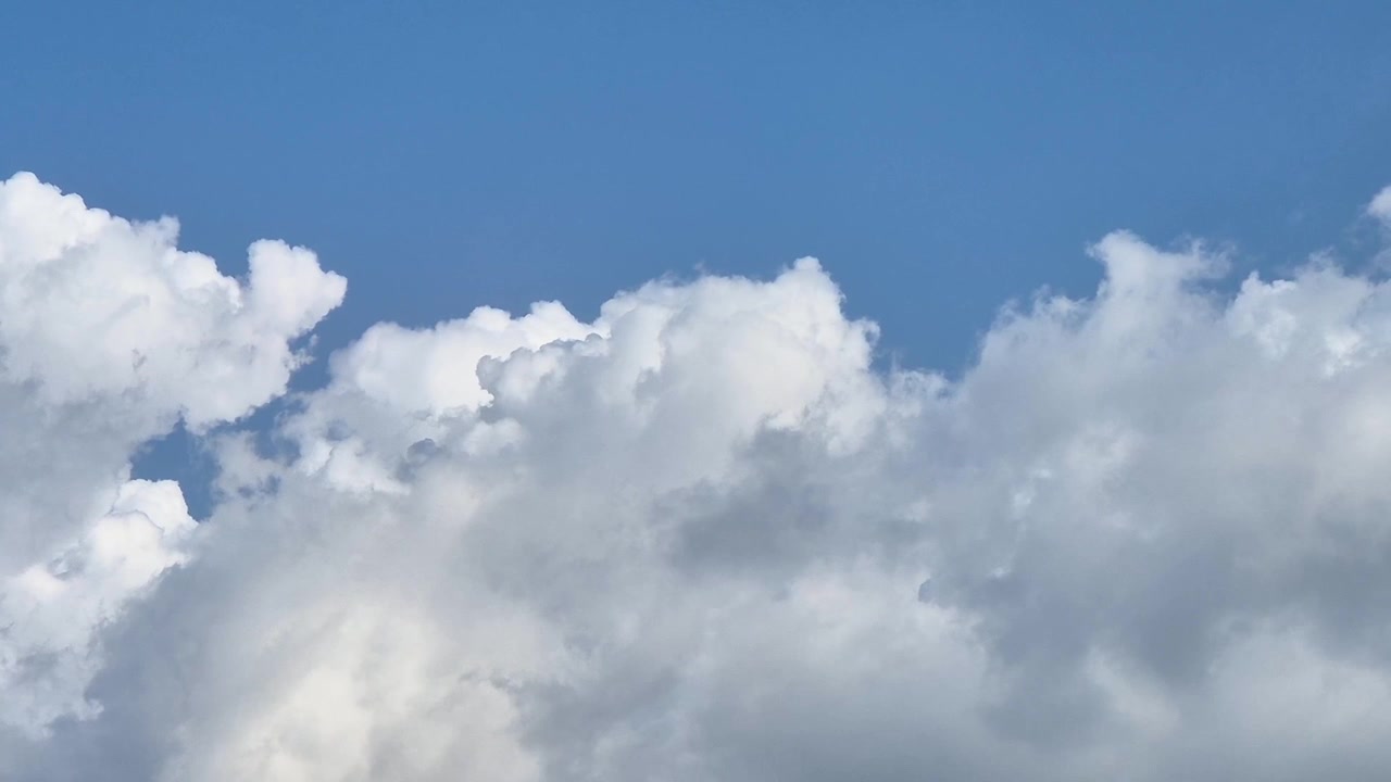Selang waktu yang diperbesar dari awan hujan gelap yang bergerak cepat melayang di atas awan putih cerah, menciptakan suasana cuaca dramatis yang ideal untuk visual sinematik dan badai