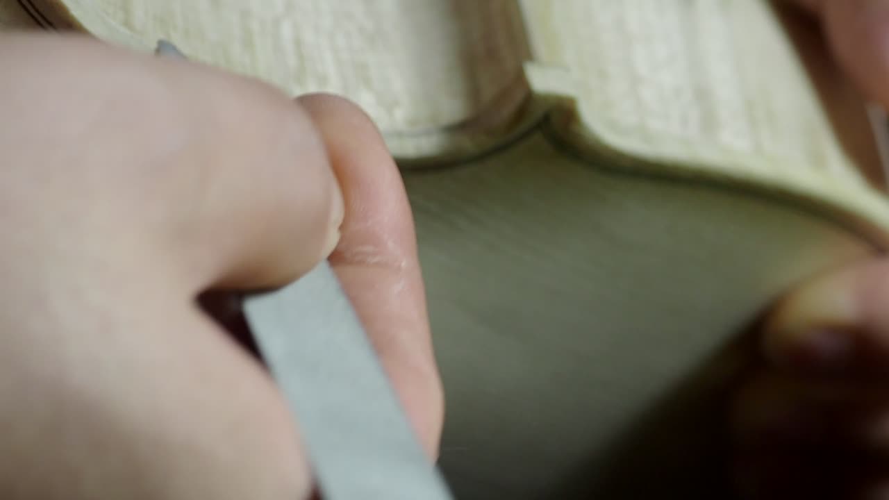 Detailed close-up of master maker using fine hand file to shape edge of a spruce violin top plate near the f-hole, showcasing craftsmanship, tradition, and meticulous attention to acoustic structure