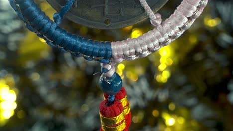 dreamy close-up shot of a chinese ancient traditional lucky coin, asian new year decoration, golden shiny blur background, square hole colorful strings, culture holyday symbol, smooth tilt up 4k video