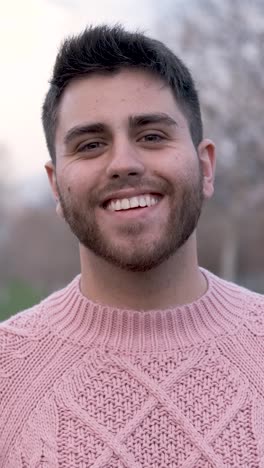 man looking at the camera and smiling while standing outdoors in the park.