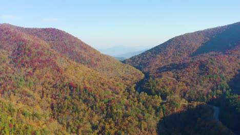 aerial pan of road winding through fall colors in north georgia mountains