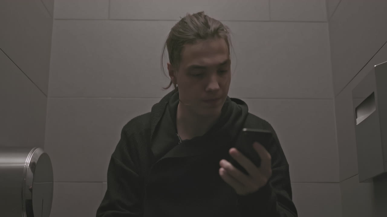 hombre sentado en un inodoro en un baño