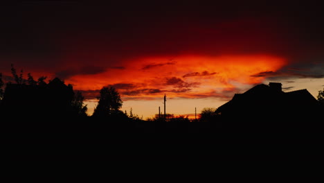 Siluetas-De-Casas-Y-árboles-Durante-El-Amanecer-Rojo-Fuego,-Drone-Ascendiendo