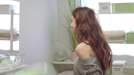 Cheerful-woman-brushing-teeth-and-rinsing-with-water-front-mirror-in-bathroom