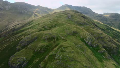 Rugged Hillside Leading Up To Craggy Mountains Crinkle Crags And Bow Fell. With Pools Of Sunshine. Summer. Lake District, Cumbria, UK
