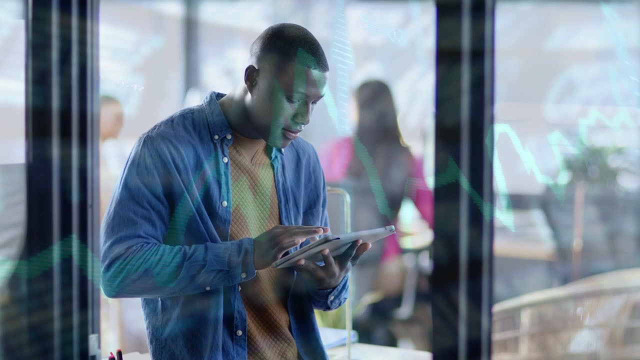 Man standing by glass tapping tablet and starting green line-graph overlay over man doing analytics