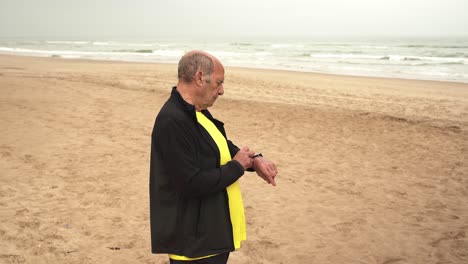 Deportista-Anciano-Comprobando-Reloj-Inteligente-En-La-Playa