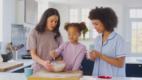 Familia-Con-Dos-Madres-En-Pijama-Haciendo-Panqueques-Matutinos-En-La-Cocina-De-Casa-Con-Su-Hija