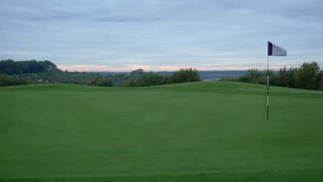 panning 4k shot of a golf course green and flag at sunrise