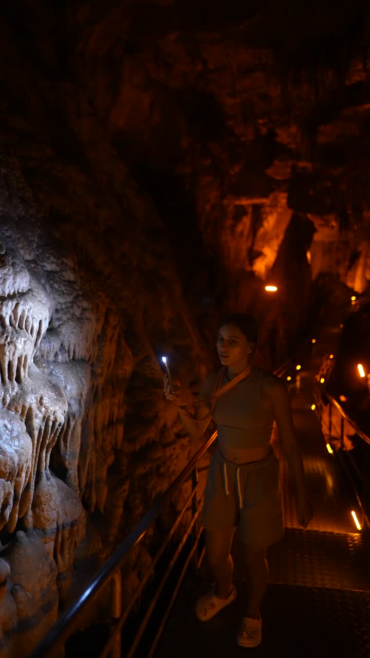 Woman exploring a cave with her phone