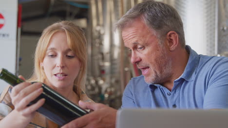 Arbeiter-Mit-Laptop-Treffen-Sich-Und-überprüfen-Die-Produktion-Im-Weingut-Mit-Lagertanks