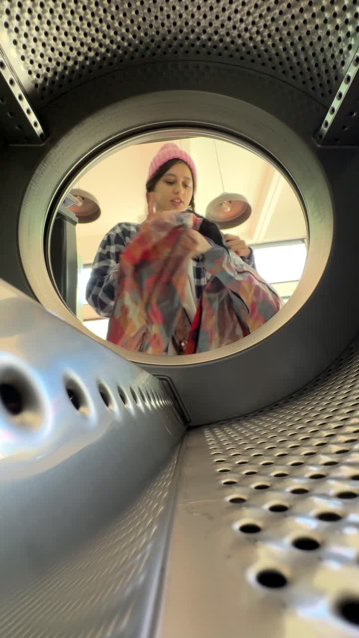 mujer cargando ropa en una secadora