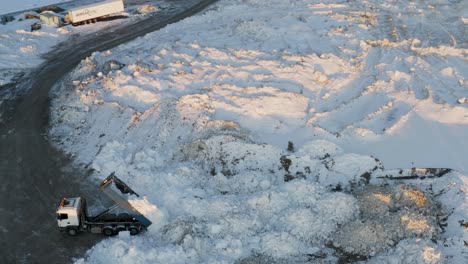 Aerial-tracking-shot-of-truck-unloading-snow-piles-to-cleaning-road-for-traffic-on-Iceland---Strong-snowstorm-at-night-in-Selfoss