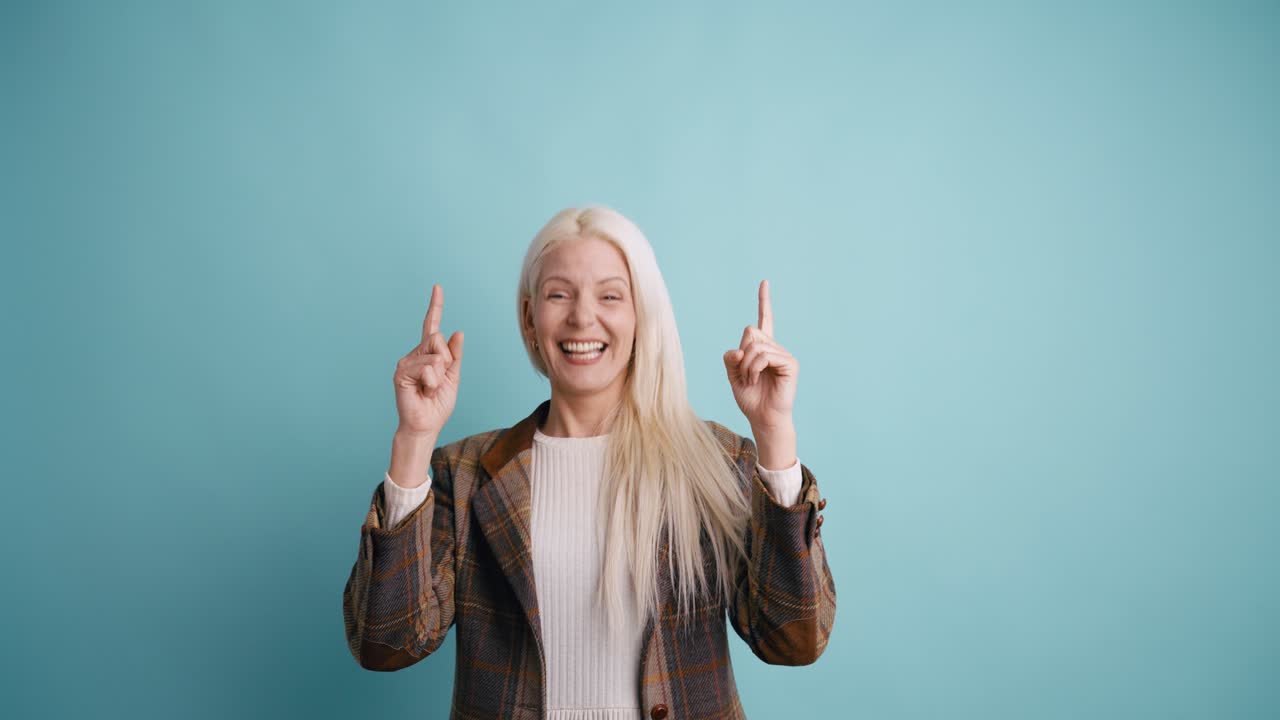 Happy Blonde Woman Pointing Upwards and Smiling